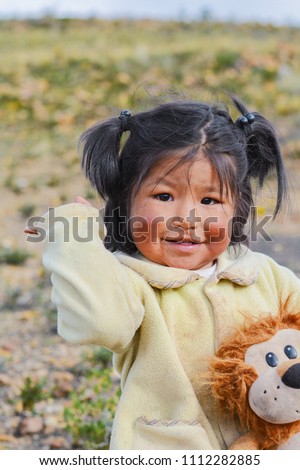 Little happy native american girl holding her toy lion in the countryside. 