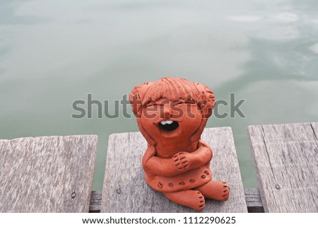 Laughing clay pottery dolls sitting on wood