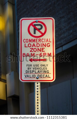 A downtown no parking sign taken during the early morning with warm sunlight illuminating it.