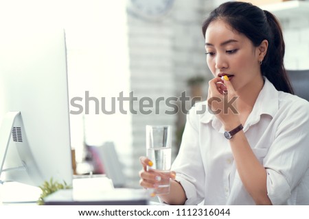 Business woman drinking water and taking medicine. She feels like sick Royalty-Free Stock Photo #1112316044