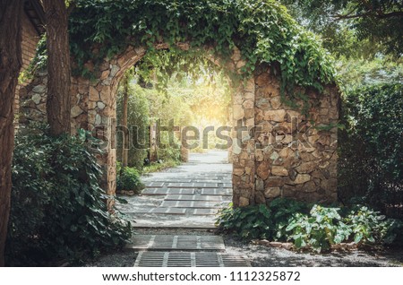 Stone arch entrance wall with ivy in the garden.
 Royalty-Free Stock Photo #1112325872