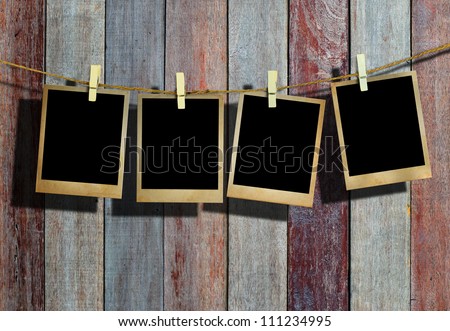 Old picture frame hanging on clothesline on wood background. Royalty-Free Stock Photo #111234995