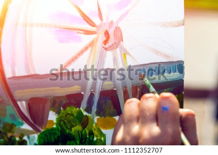 Close-up of a woman artist paints on canvas and an easel with oil paints in a city park on a sunny day