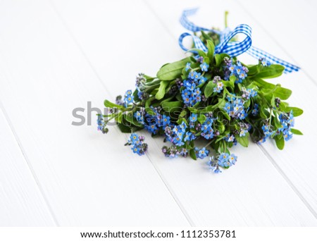 Forget-me-nots flowers with ribbon on a wooden background