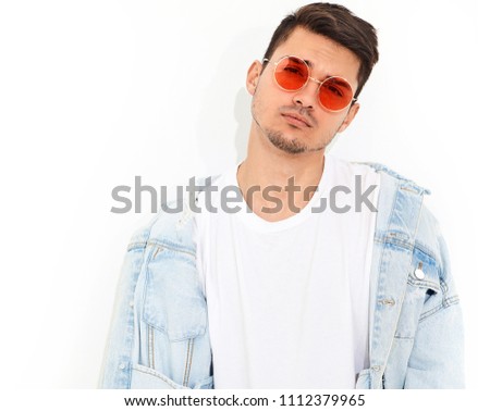 Portrait of handsome young model man dressed in jeans clothes in sunglasses posing on white background. Isolated