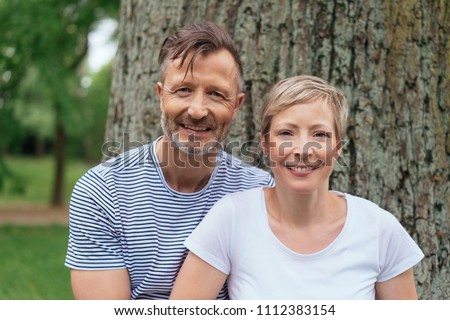 Portrait of a happy middle-age couple looking at camera while posing outdoors in the park