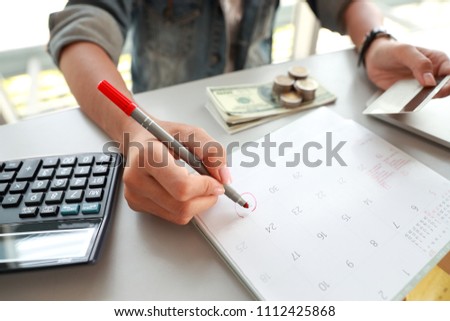 businesswoman paying monthly and holding credit cards and writing on calendar  (this image for business and technology concept)
