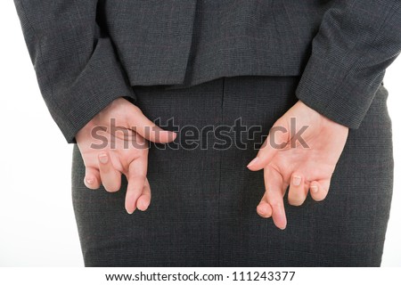 Business woman in suit holding crossed fingers behind back - concept for good luck or dishonesty