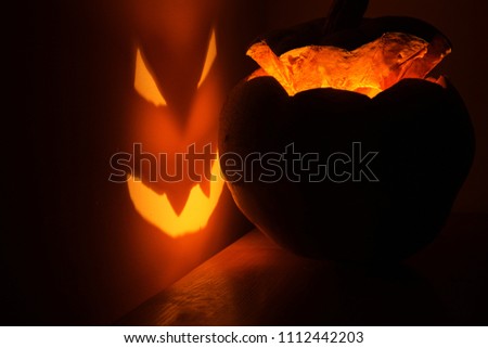Illuminated Halloween pumpkin in the dark, smiling against the wall
