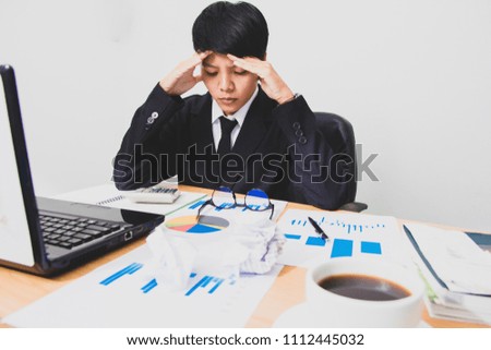 Asian young man in black suit are stress worry probleme working sitting on chair in office.