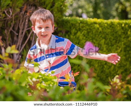 Cute and adorable Caucasian boy in a striped shirt playing in the park in the summer.