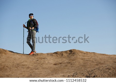Image of tourist woman in jacket with backpack and walking sticks