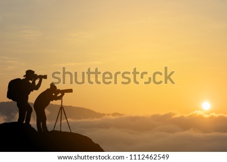 silhouette of a photographer who shoots sunset on background.