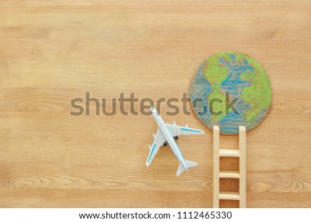 top view image of airplane earth globe and ladder over wooden background