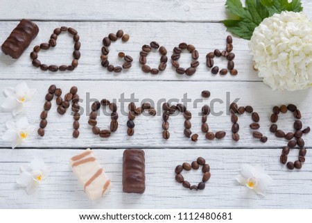 The phrase "Good morning" of coffee beans, laid out on a wooden white background