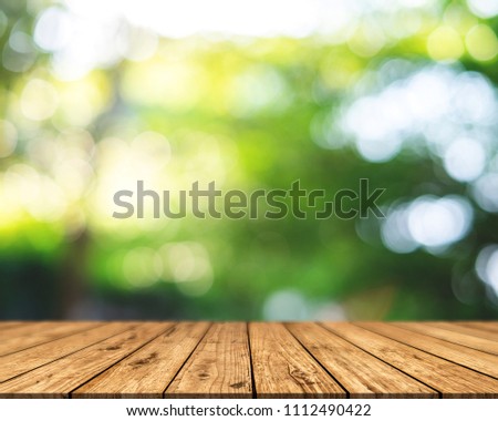Brown wood surface on a green background. Green leaf background, blurred sun, abstract bokeh can be used for displaying or editing your product. Royalty-Free Stock Photo #1112490422