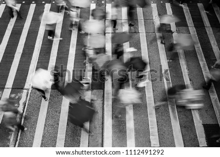 Motion blurred pedestrians crossing Hong Kong street in the rain (black and white)