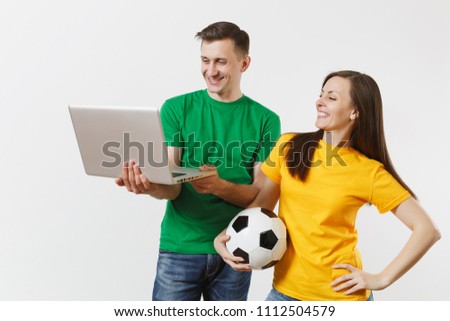 Young couple, woman man, football fans in yellow green t-shirt cheer up support team with soccer ball, watching game on pc laptop isolated on white background. Sport family leisure lifestyle concept