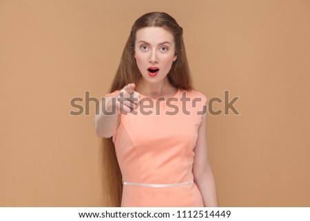 wow, is that you? portrait of emotional cute, beautiful woman with makeup and long hair in pink dress. indoor, studio shot, isolated on light brown or beige background.