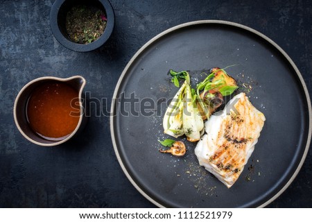 Modern Thai fried cod fish filet with bok choi and mushroom as top view on a plate 