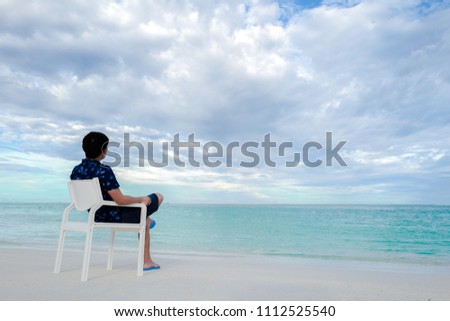Summer concept , A man relax sit on white chair on the beach white sand and turquoise sea color at maldives on the weekend holidays