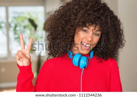African american woman wearing headphones showing and pointing up with fingers number two while smiling confident and happy.