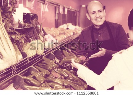 Portrait senior worker selling vegetables to female customer 