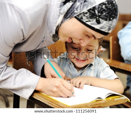 Muslim Arabic teacher working with little kid at school