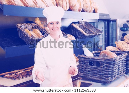 Bakery female employee with tasty and fresh bread products on counter
