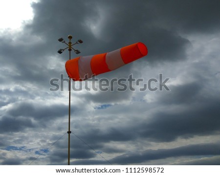 Windsock in windy weather with  storm cloudy sky Royalty-Free Stock Photo #1112598572