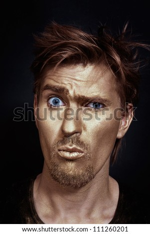 Funny man with golden make-up on a black background