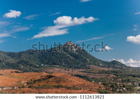 View from the window. Mountains in summer. Blue sky and clouds. Trees and fields. Small houses. Russia