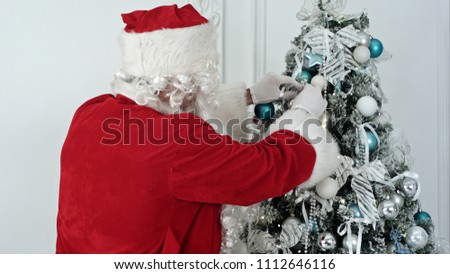 Santa Claus decorating Christmas tree