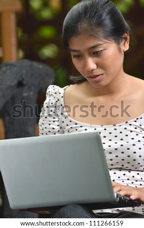 A young pretty southeast asian girls using a laptop at outdoor scene