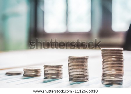 Silver coins placed in piles on desk with light sunset and  instagram style filter photo vintage tone