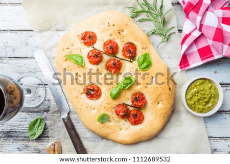 Traditional Italian Focaccia with tomatoes and rosemary - homemade flat bread focaccia over wooden background, top view