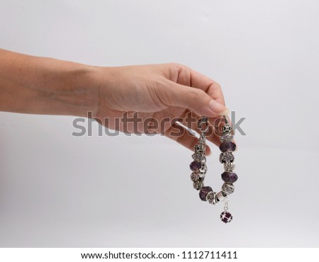 Luxury silver bracelets in women hand on white background. Violet bracelets in hand.