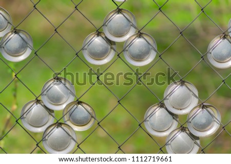 Metal chain-link fence decorated metal circles on a green grass background