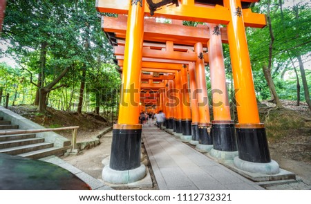 Wide angle bottom view view of Torii gates in Fushimi Inari Shrine with blurred people, long exposure, Kyoto, Japan