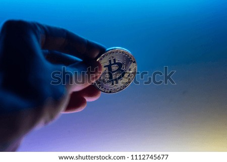 close-up of a hand holds bitcoin in the neon light of a crypto currency