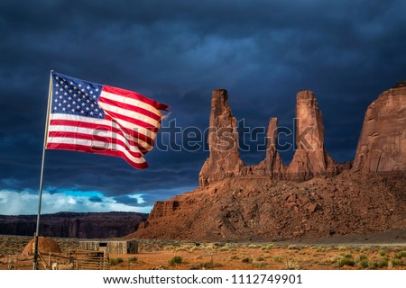 American flag flutters in the wind with storm in the background at Monument Valley, Arizona, USA.