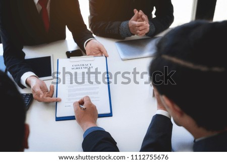 closeup hand of business man signing contract document and handshaking after finished meeting.