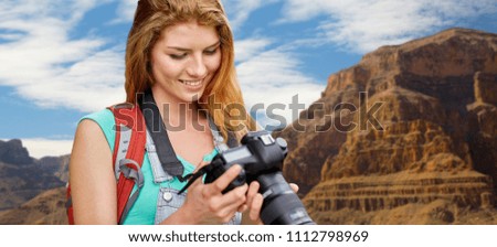 travel, tourism and photography concept - happy young woman with backpack and camera photographing over grand canyon national park background