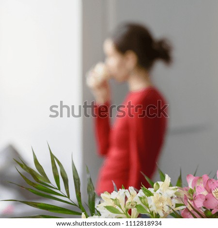 Blurred photo of woman having break and drinking coffee near window