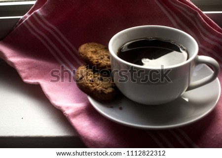 
Chocolate chip cookie on silver metal surface and a cup of coffee