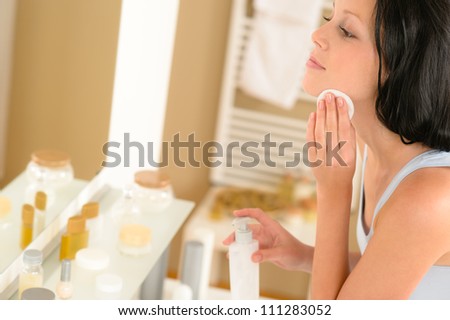 Young woman in bathroom clean face make-up removal looking mirror Royalty-Free Stock Photo #111283052