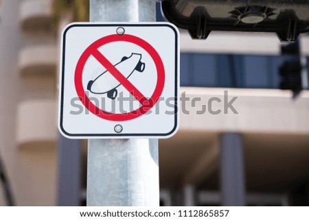 No Skate Boarding sign on a city lamp post, with an office building in the background and space for text on right