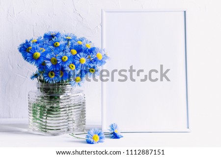Front view blank mock up of photo frame on the white background. Blue flowers on a white wooden table background with copy space. Home floral interior.