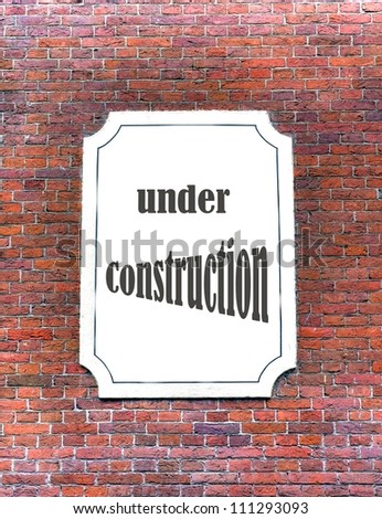 under construction sign on a brick wall with a white board