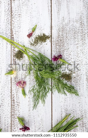 Tarragon, Rosemary, Chives, Sage, Marjoram and Dill herbs on a rustic table top with edible flowers